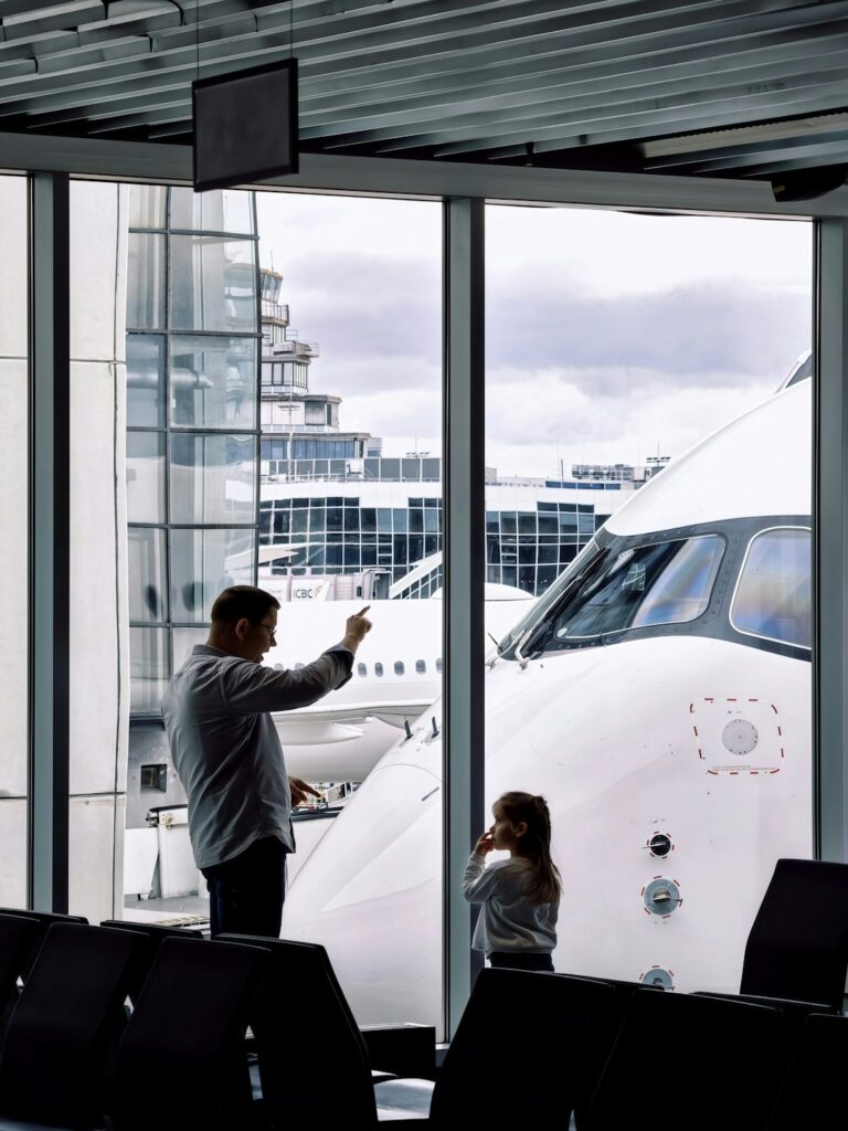 Father and daughter looking out at an airplane through the gate window