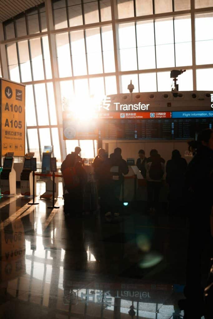 Travelers walking through an airport terminal with sunlight streaming in